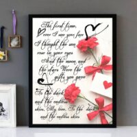 Framed wall art with black text of the song lyrics from the song First Time Ever I Saw Your Face by Roberta Flack, with red flowers on a distressed wooden boards background.
