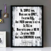 Framed wall art with black text of the song lyrics of Somewhere Only We Know by Keane, with a weathered floorboard background.